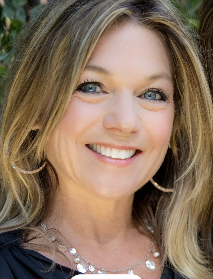 A woman with long hair and blue eyes smiling.